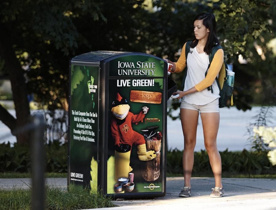 A student throws her coffee cup into one of several solar powered trash compactors surrounding Central Campus.