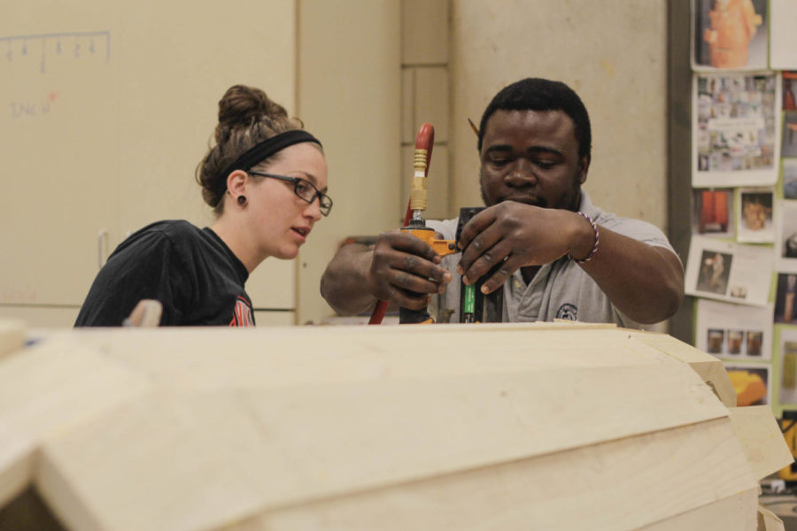 Eric Adjetey Anang is a Ghanaian carpenter and coffin artist who will be with the College of Design until Friday to work with integrated studio arts students. Together they will be creating a coffin shaped like an ear of corn. Students are working on the coffin and the paint designs.