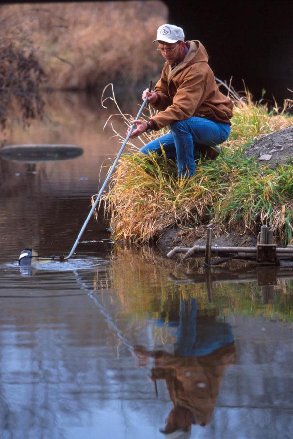 Jeff Nichols, a technician at the National Laboratory for Agriculture and the Environment, collects a water sample from Walnut Creek south of Ames. The U.S. Department of Agriculture is studying the effects of farming practices on water quality.