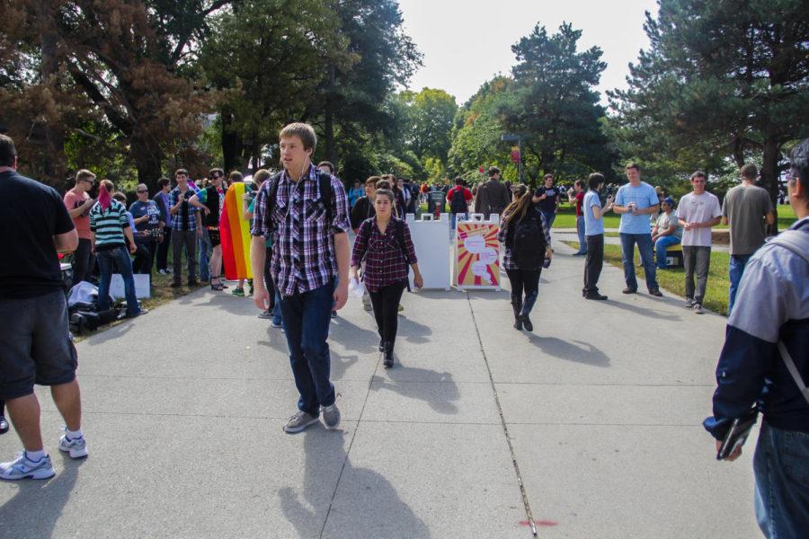 Students walk past evangelist Pastor Tom Short while the LGBTQA community and Atheist and Agnostic Society protest in the free-speech zone in front of Parks Library on Sept. 25.