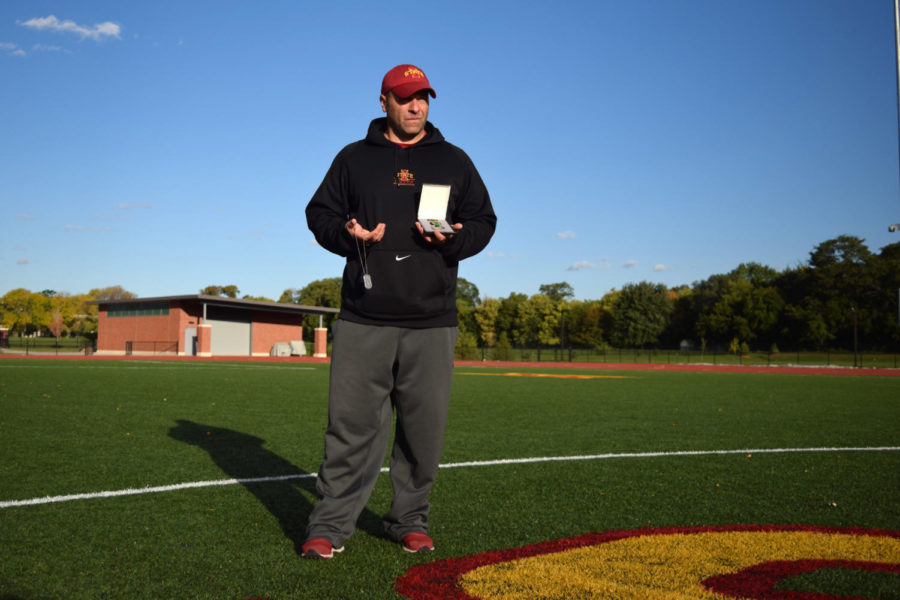 Soccer coach Tony Minatta stands with his dog tags and his Navy achievement medal at the Iowa State Soccer Complex Tuesday Oct. 7. Minatta served in the Marines before taking the coaching job at Iowa State.
