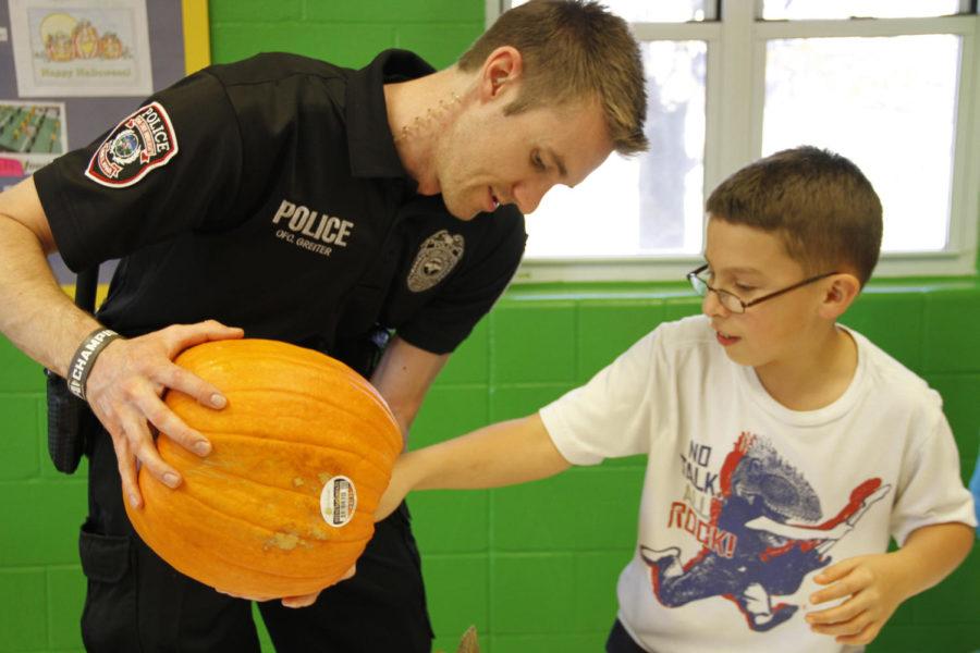 Anthony Greiter of the ISU Police Department helps 10-year-old Carlos carve a pumpkin on Oct. 29 at the Ames Boys and Girls Club. Local police helped youth carve pumpkins as a part of a police outreach program. 