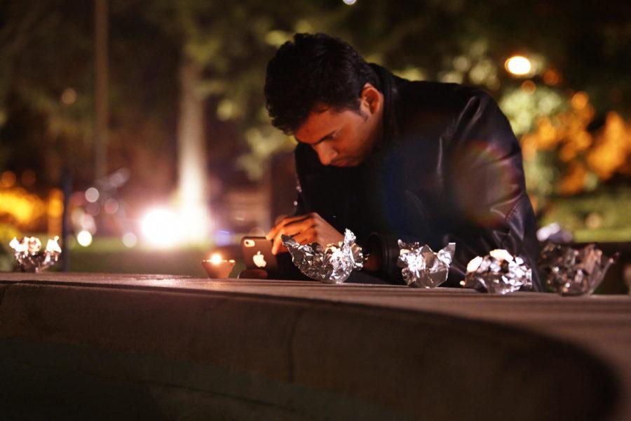 Vishel Mane takes a picture of the candles at a Diwali celebration at the Fountain of the Four Seasons outside the Memorial Union. The event, which took place on Oct. 22, is a celebration of the victory of light over darkness and is celebrated by many cultures in Asia.