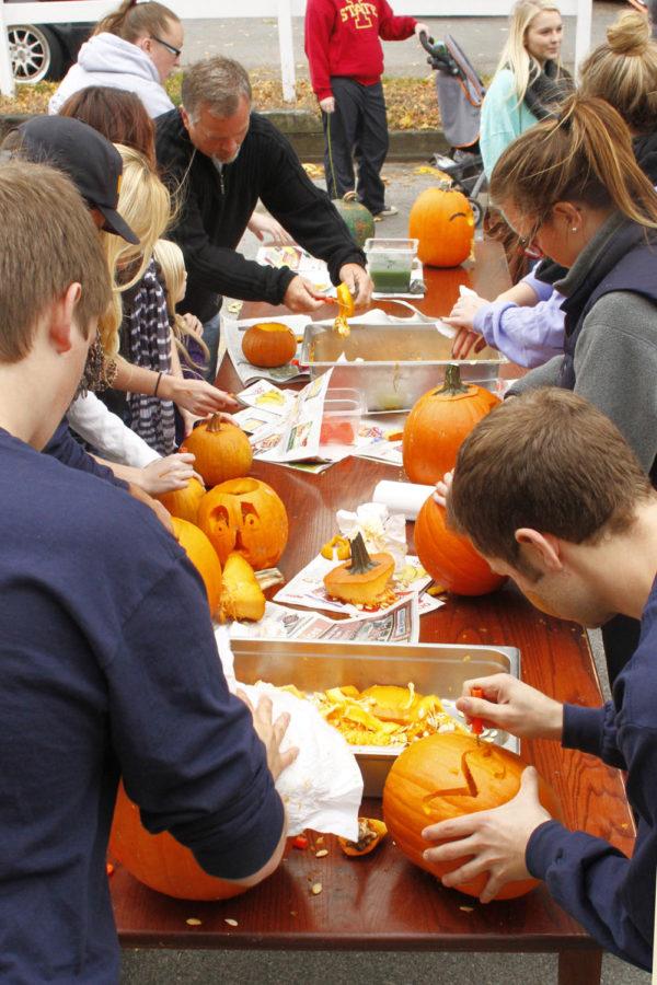 Family and friends gather around and carve pumpkins on Sunday, Oct. 20, on the Sigma Alpha Epsilon driveway.