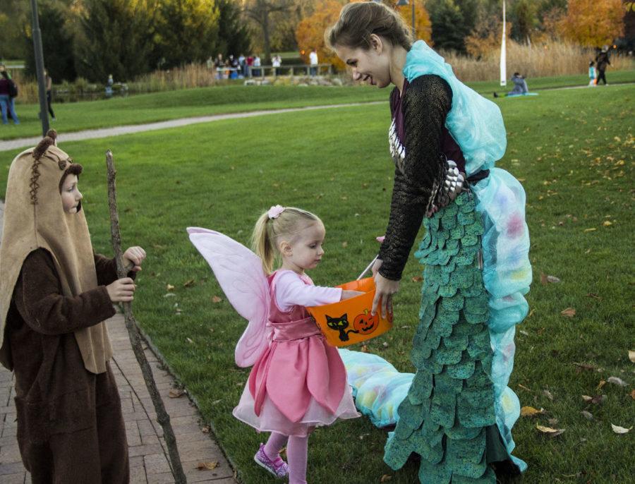Alyssa Priebe, sophomore in apparel, merchandising and design, wears a mermaid costume created by Jorden Charron, junior in apparel, merchandising design, at Spirits in the Gardens at Reiman Gardens on Oct. 25. Jane, 3, and Adam, 6, take some candy from her bucket at the event.
