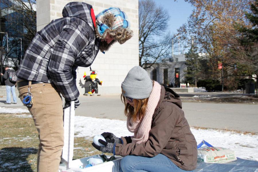 An ISU student helps Savanna Falter, freshman in pre-industrial design, pick out a balloon to throw at Gamma Rho Lambdas interactive art piece to observe the Transgender Day of Remembrance on Nov. 20 outside of Parks Library. Participants of the activity paid $1 to throw a balloon full of paint at a board of nails to create a piece of art. Each balloon had a message written on it to remember transgender people who have passed away. All funds are being donated to a local charity aimed at transgender support.