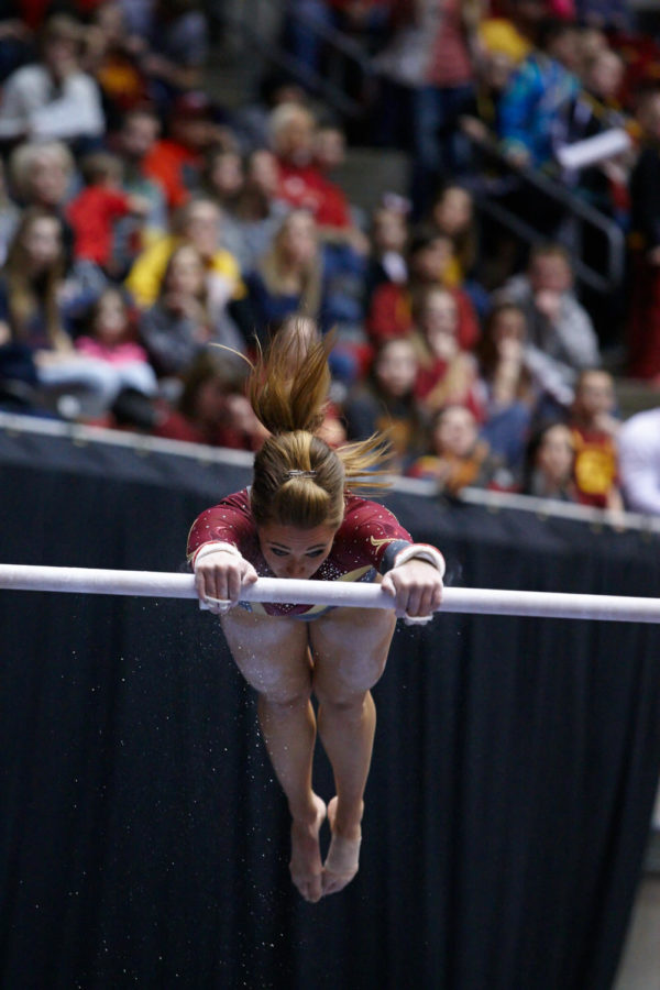 Chalk sprays from senior Caitlin Browns hands as she grabs on to the uneven bars.
