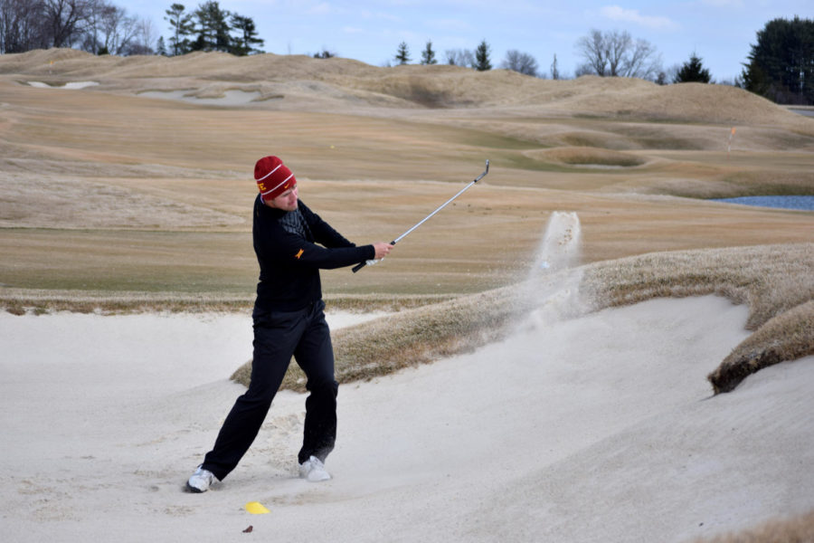 Sophomore Jack Carter hits the ball out of a bunker during practice on Thursday at the teams practice facility south of Ames.