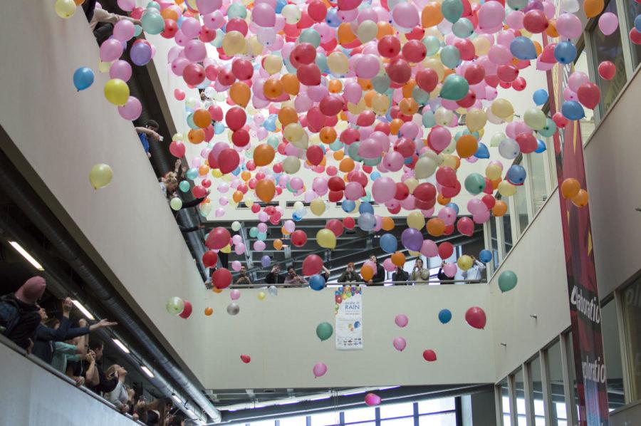 Balloons, some of which contain money, are dropped onto design students waiting below. The balloon drop took place March 4 in the atrium of the College of Design.