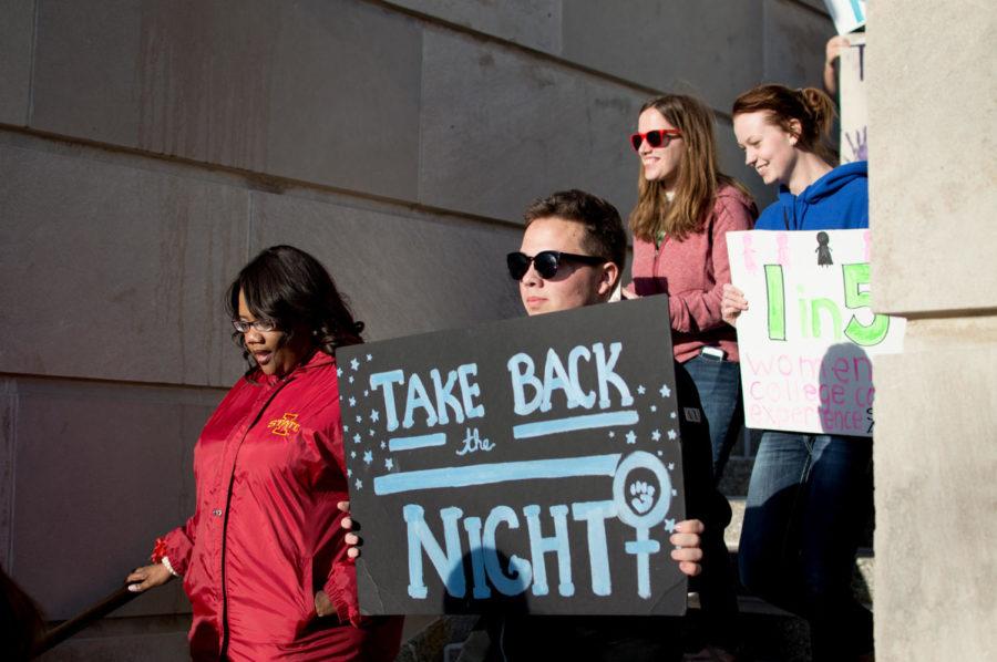 Participants of Take Back the Night walk hold signs while walking through campus. The event was provided April 22 to promote awareness about sexual assault.