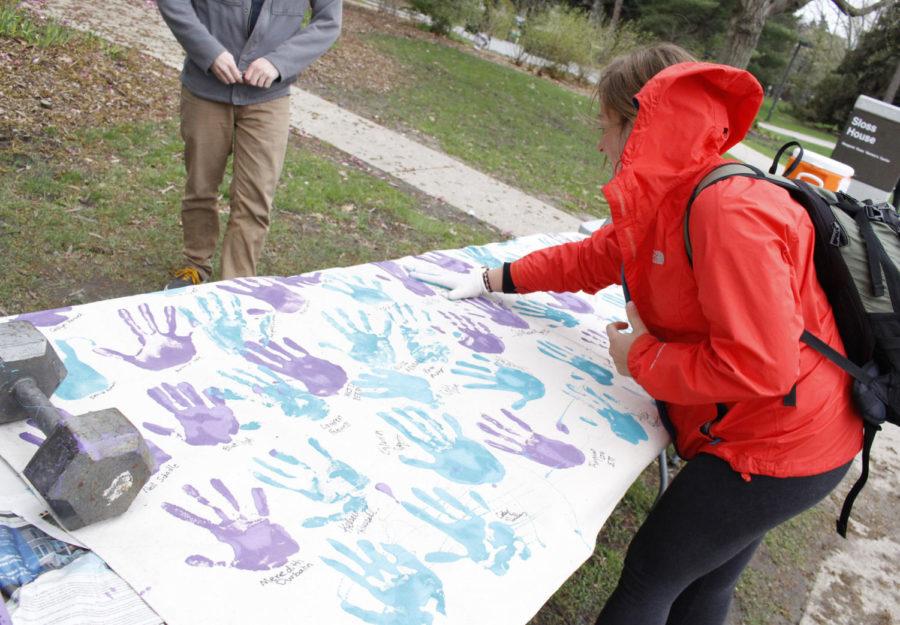 Abby Barten places her handprint on the banner at “These Hands Don’t Hurt,” an event to help raise sexual assault awareness at the Margaret Sloss Center on April 20 from 8 a.m. to 2 p.m. Several ISU students pledged to never hurt anyone with their hands by placing their handprint and signature on the “Promise Wall.”