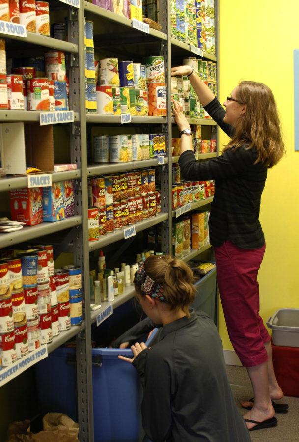 Jessica Schaumburg (bottom), president of the SHOP, helps organize the shelves with Abby Rubsam, a volunteer. Schaumburg said the SHOP receives most of its stock from other student organizations.