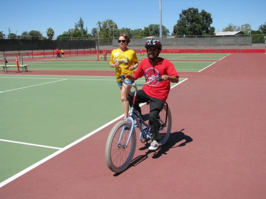 Ciara McCarty, senior in kinesiology, jogs alongside one of the participants of the iCan Bike camp in Fresno, Calif. last summer. 