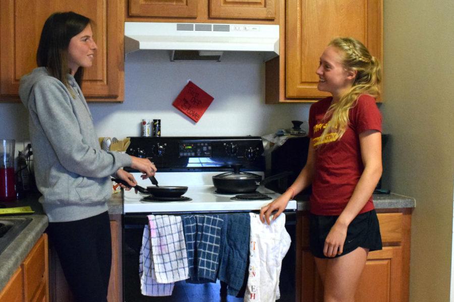 Senior Crystal Nelson,left, and junior Bethanie Brown, right, cook over the stove in their West Ames apartment on Tuesday.