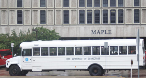 An Iowa Department of Corrections bus sits empty in front of Maple Hall on July 28, 2015, as inmates inside the residence hall move and install furniture.