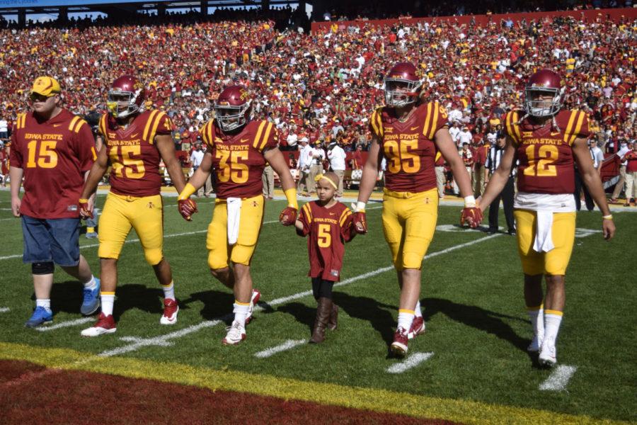 Maddy Snow (center) walks with the ISU team captains to midfield before the coin flip at the Cy-Hawk football game on Saturday.