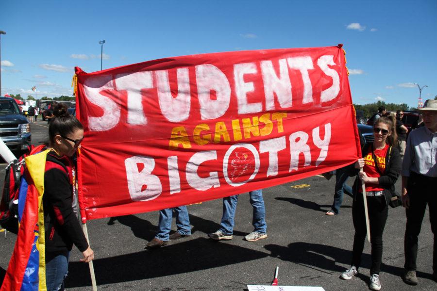 Graduate student Maria Alcivar (left) and sophomore Michelle Ramos (right) protest against political bigotry during a Republican meet-up on Saturday outside Jack Trice Stadium. 