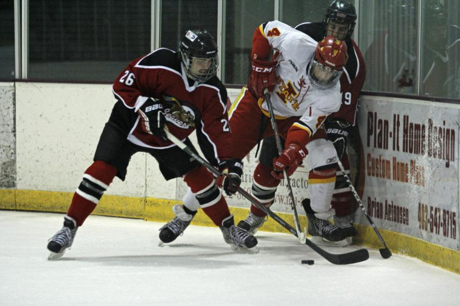 Sophomore left defenseman Cory Sellers fights to get the puck from two Beavers players on Friday, Nov. 15, during the first of two matchups against Minot State. The Cyclones defeated the Beavers 2-1.