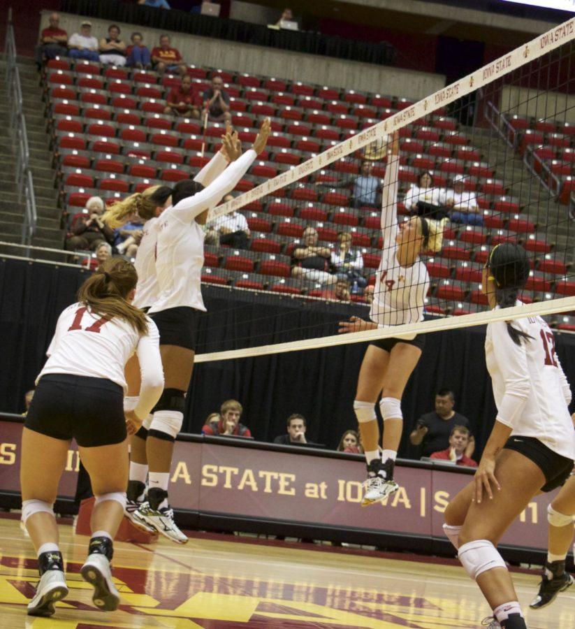 Freshman outside hitter Jess Schaben goes up for the spike on the opposite side of the net, while two other players try to block it during the Cardinal and Gold scrimmage match on Aug. 22. 
