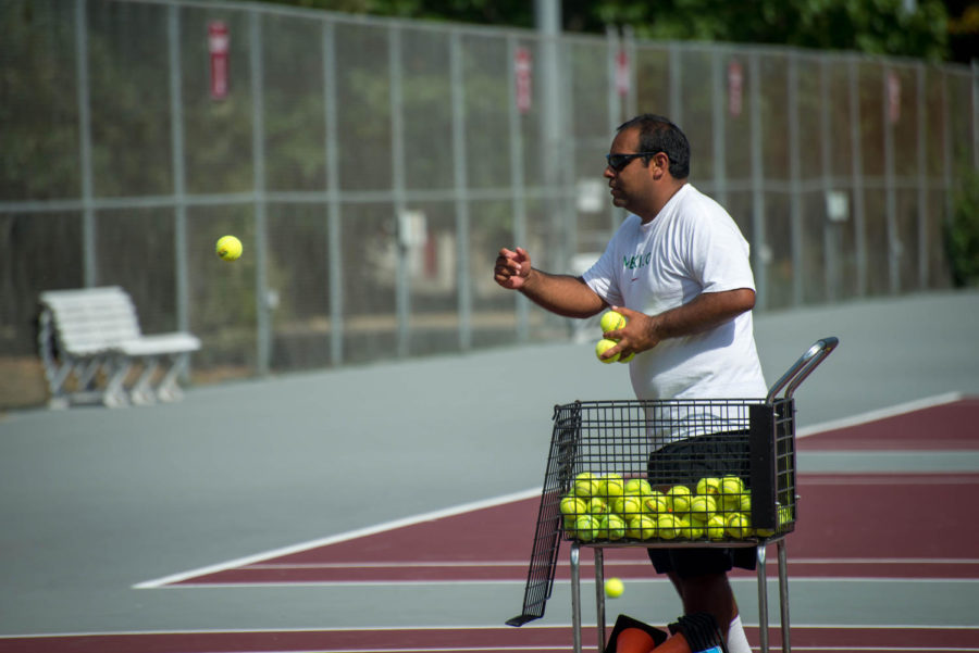 Armando Espinosa, head coach of women tennis, is practicing with the Iowa State tennis players by throwing the tennis balls towards them to hit.