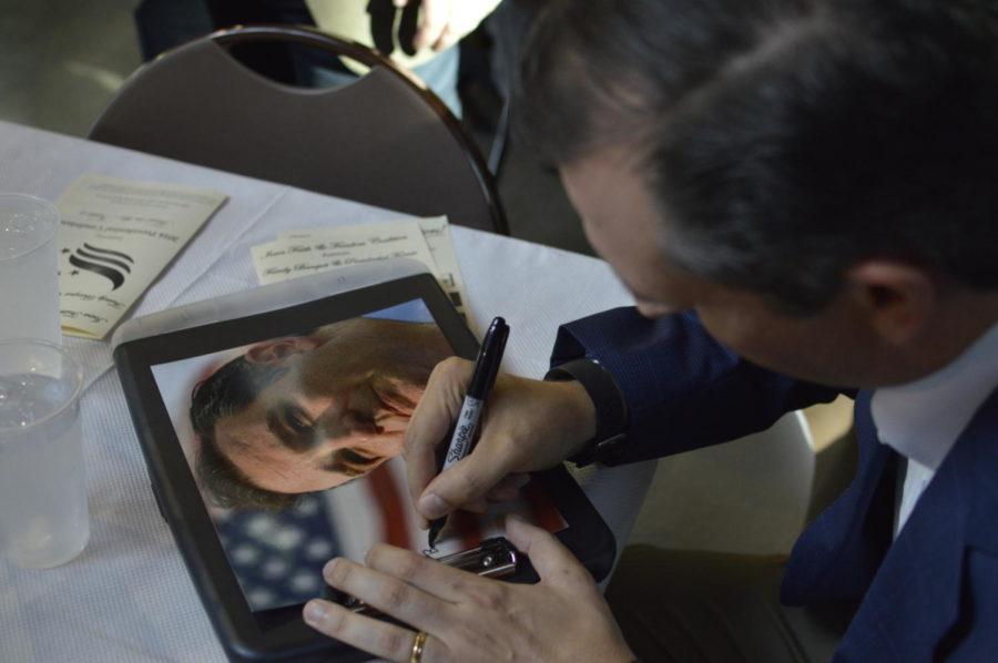 U.S. Sen. Ted Cruz signs a photo of himself for a supporter at the Iowa Faith and Freedom Coalition Dinner on Sept. 19.