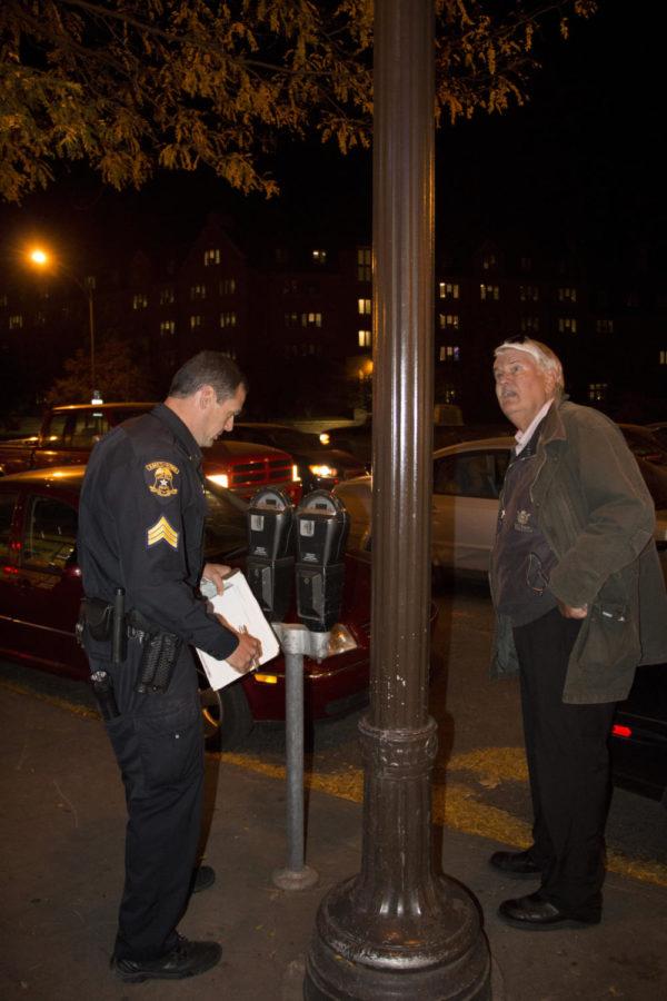 Sergeant Derek Grooters of the Ames Police Department analyzes a problematic streetlight at the Campustown safety walk Thursday evening. The safety walk is an annual event that highlights concerns that include burnt out streetlights, overgrown shrubs, and problematic sidewalks. 