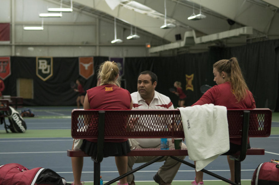 ISU tennis coach Armando Espinosa speaks to ISU tennis players after a set during their match against Texas on March 27, which ended in a 4-2 loss to Iowa State. 