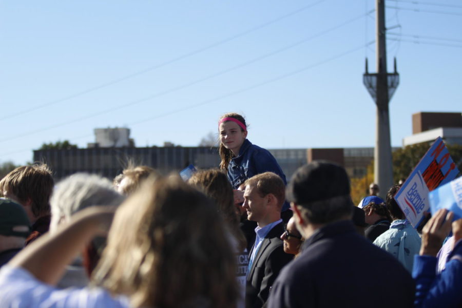 A young attendee sits above the crowd in Des Moines at the Bernie Sanders rally before the Jefferson-Jackson Dinner.