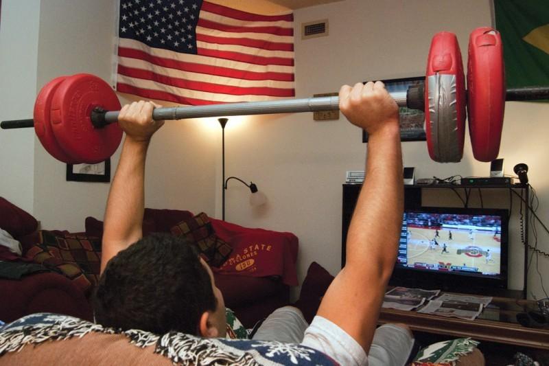 Eric Ely, senior in psychology, lifts weights from the comfort of his living room to sweat off some stress during finals.