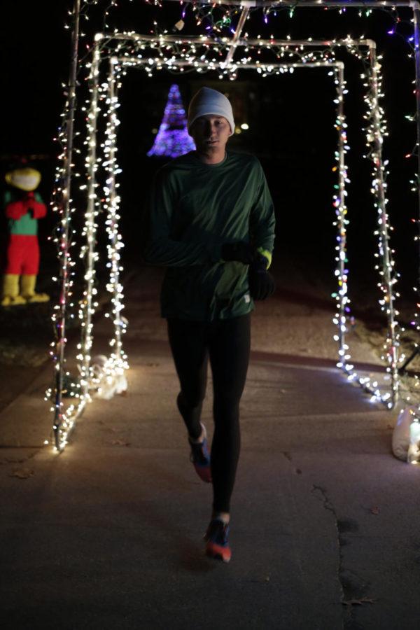Mason Frank, senior in math education, is the first runner to pass through columns of christmas lights which mark the finish line of the 2013 Jingle Jog race outside of Curtis Hall on Dec. 6. Runners started at Beardshear Hall from where they loop around by the Design building over to lead and back over to Curtis Hall all while enduring subzero temperatures. “The Living History Farms race was worse,” said Frank.