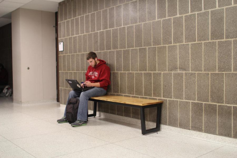 A student sits on one of the new benches on the second floor of Carver. Many new benches have been placed in high-traffic areas around campus.