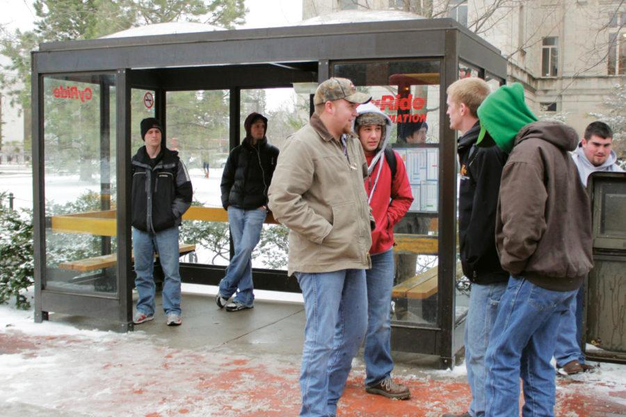 Students huddle together trying to keep warm while waiting for their buses outside the CyRide stop near Parks Library on Wednesday, Feb. 29. The National Weather Service issued a wind advisory for Ames on Wednesday, as strong gusts and snow combined for frigid temperatures and blizzard conditions throughout the day. 
