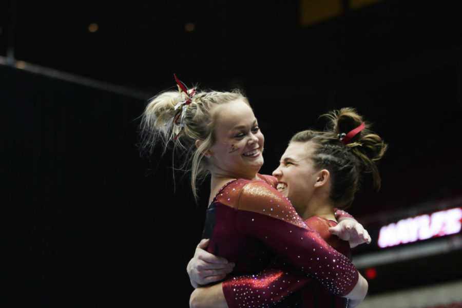 Haylee Young, sophomore, hugs Kelsey Paz, sophomore, after finishing her uneven bars routine Jan. 23. 
