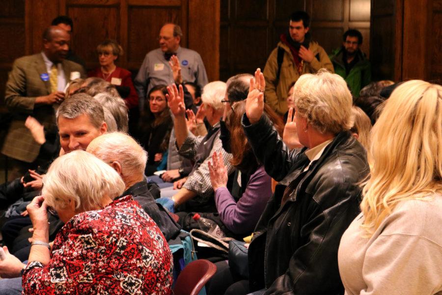 Caucus members in the Grand Ballroom at the Memorial Union raise their hands to signify that their vote has been counted. 