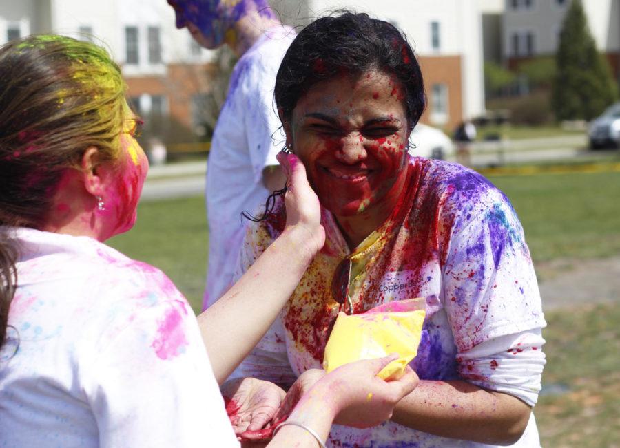 Bhakti Bansode, the vice president of the Indian Students Association, grins as another students rubs paint on her face during Holi on Saturday afternoon. 