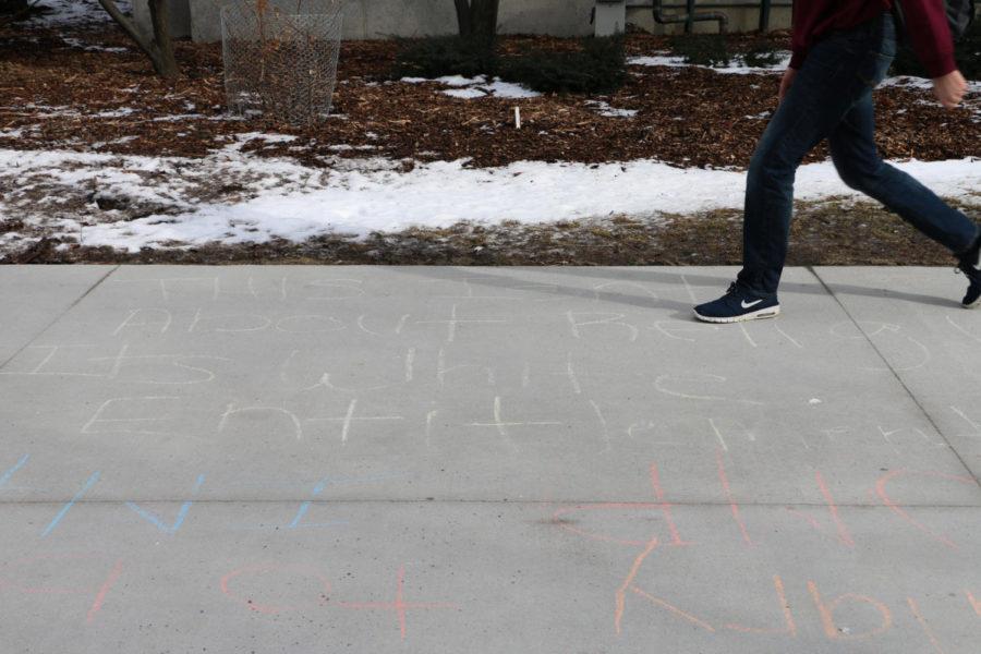 A student walks over a chalking reading "This isn't about religion, it's white entitlement." Several chalk writings relating to President Donald Trump's executive order suspending immigration from seven countries were spread on the sidewalk behind Beardshear Hall Jan. 30, 2017.