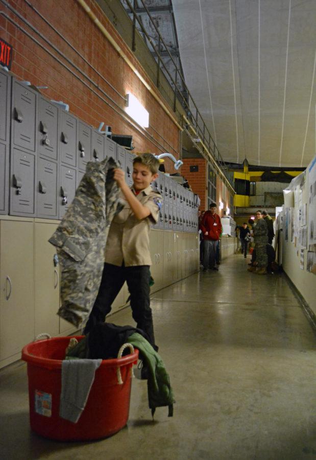 A Boy Scout grabs a jacket from a bucket of clothing during an activity conducted by the ISU Army ROTC staff at the 30th Winter Survival Training event held in the Armory on Jan. 28.