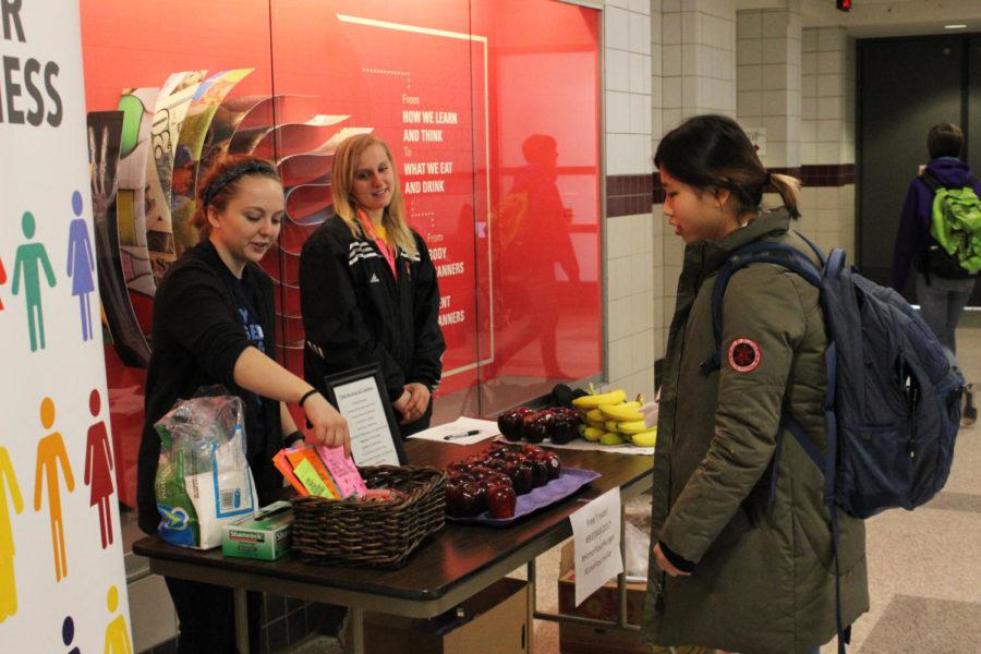 Junior Jade Gibson and senior Megan Tisue hand out fruits and granola bars at the Honor Your Hunger event in Lebaron Hall on Feb. 27. The event is run by Body Image and Eating Disorder Awareness to promote positive body image.