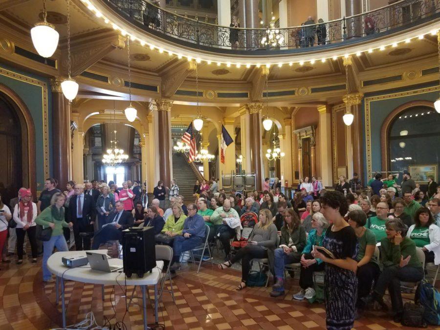 A crowd of people watch a live stream of a public hearing just outside of the Capitol Buildings Supreme Court Chambers, which was a full standing and seating capacity, in Des Moines on Monday.