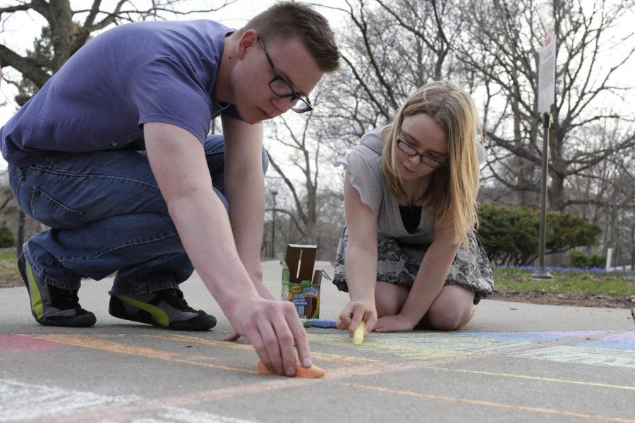 Ben Duran and Angela Dunkin draw a rainbow-colored kite on the sidewalk by the Campanile as part of LGBT Pride Week on April 20, 2014. Duran and Dunkin, along with junior Brian Gill and sophomore Amy Barnhart, walked around campus coloring on the sidewalks and writing notes to raise awareness for the week and to advertise events.