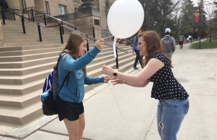 A member of the Suicide Awareness Organization hands out a balloon to a student.