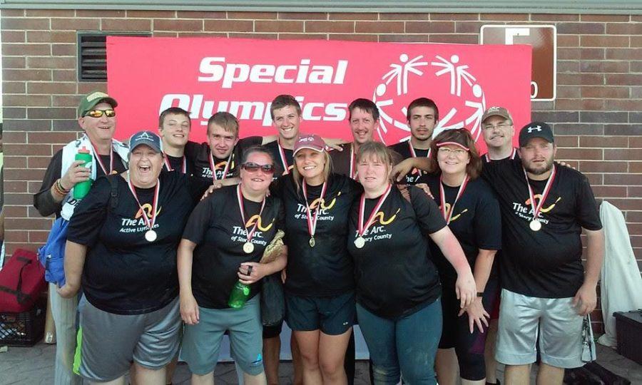 Lauren Wernau with her team stand in front of a Special Olympics banner.