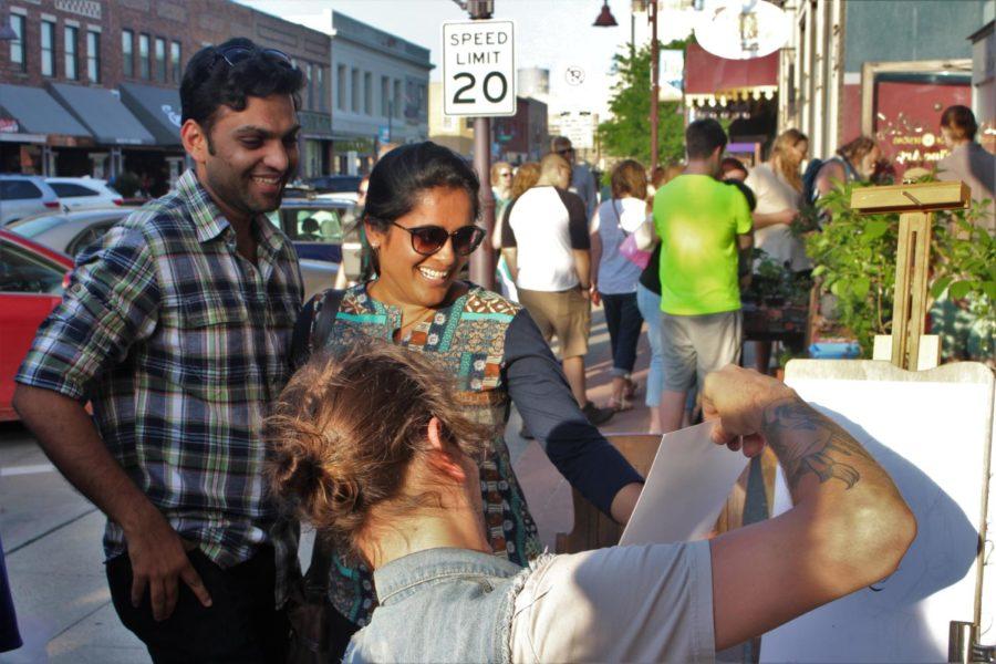 On Main Street in Ames, Henry Kaufmann presented Anant and Kavita Jain their caricature drawing on June 2.