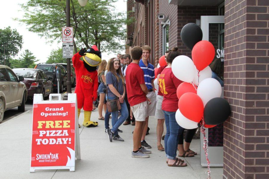 People wait on Lincoln Way to get free pizza at Smokin' Oak's grand opening on June 29. Smokin Oak is now third pizza restaurant in the Campustown portion of Lincoln Way.