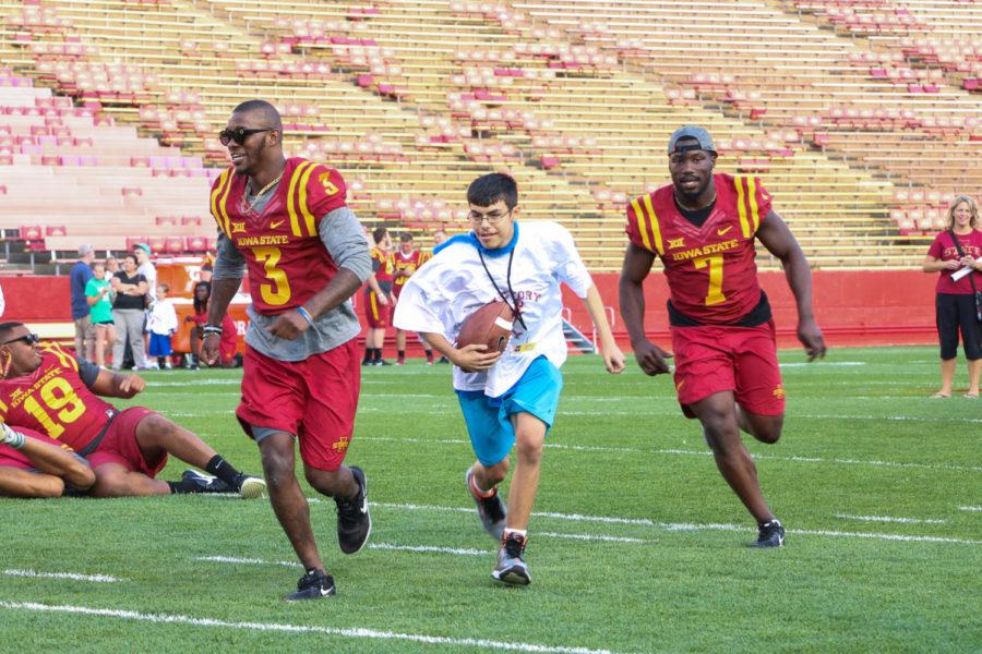 Dallas Cooper runs down the field for a touchdown alongside Reggie Wilkerson (3) and Willie Harvey (7) during Victory Day on Aug. 25. Victory Day gives children with disabilities the opportunity to meet and participate in drills with Cyclone football players.