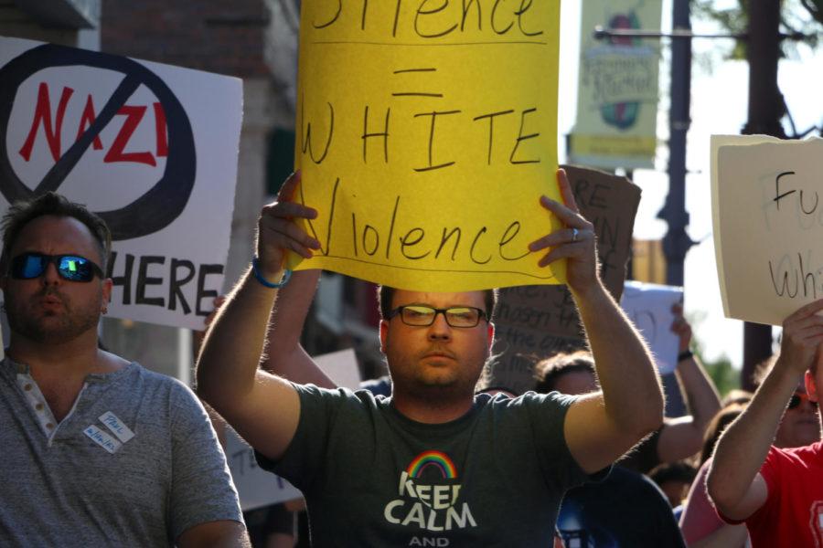 Joel Hochstein, a program coordinator in the Dean of Students Office, holds a sign reading White Silence = White Violence during the Ames Stands Together Opposing White Nationalism event Sunday, Aug. 13. 
