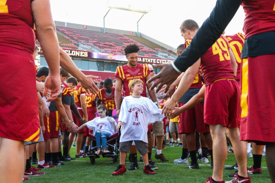 Kalvin Gibbons makes his way through the tunnel of football players before the start of Victory Day on Aug. 25. Victory Day gives children with disabilities the opportunity to meet and participate in drills with Cyclone football players.