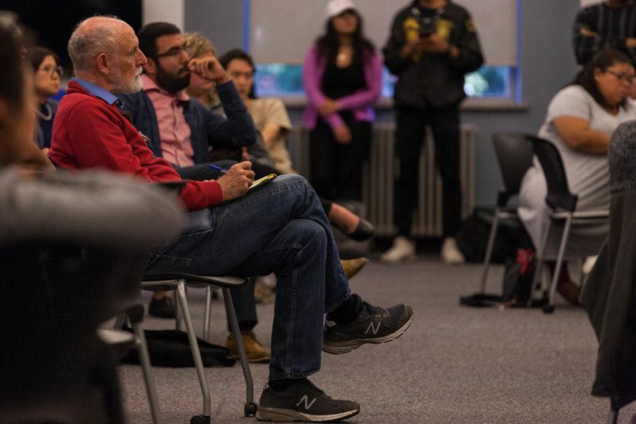 Jan Flora, professor emeritus of Iowa State, listens to the panel of community experts as he jots down notes at the Know Your Rights forum Thursday evening at Parks Library 198.