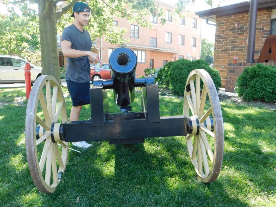 Alpha Sigma Phi Vice President preps the fraternity's cannon to fire in front of the chapter's house.