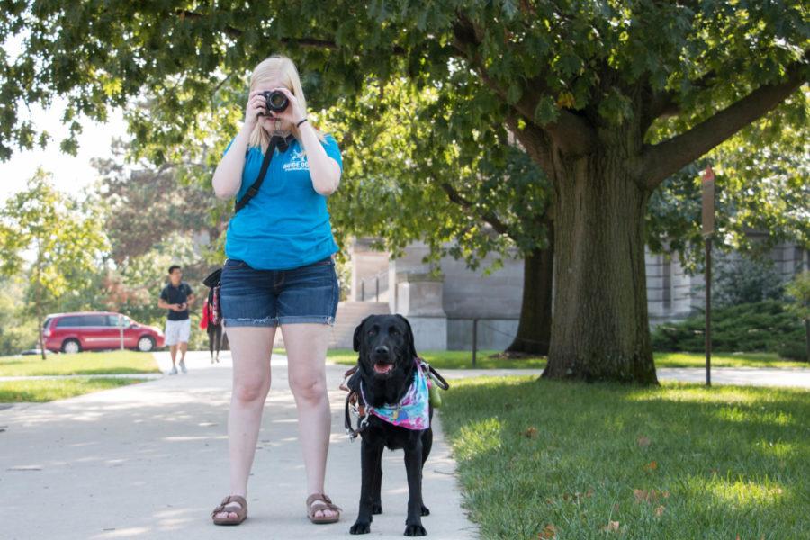Lauren Berglund takes a photo of Morrill Hall with her guide dog, Sheba, by her side. Lauren was born with oculocutaneous albinism, a condition that causes a lack of pigment in her skin, hair and eyes. She uses photography as a way to capture the details she cant see with her naked eye. 
